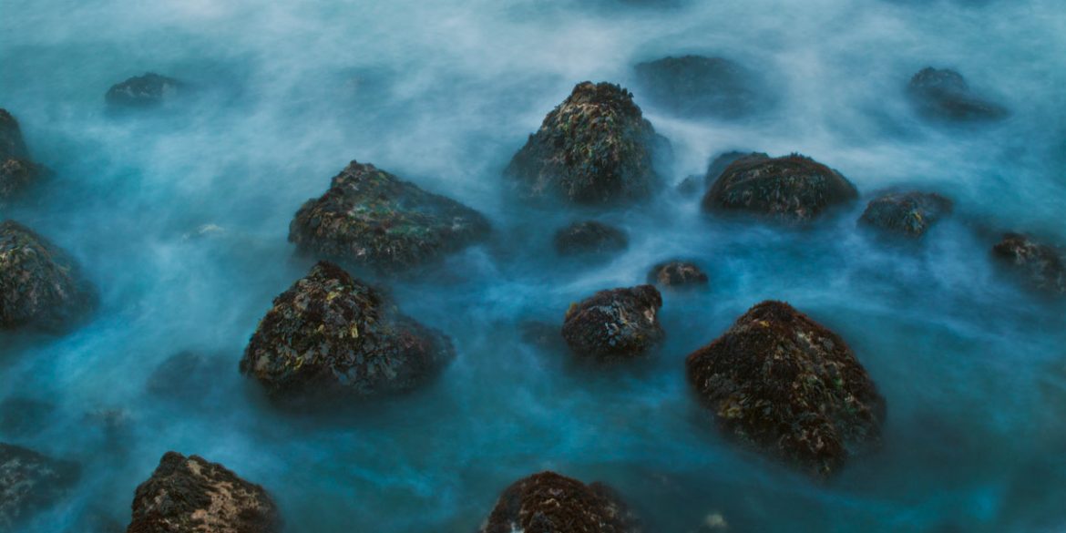 A long exposure photo of a rocky seashore on the California coast