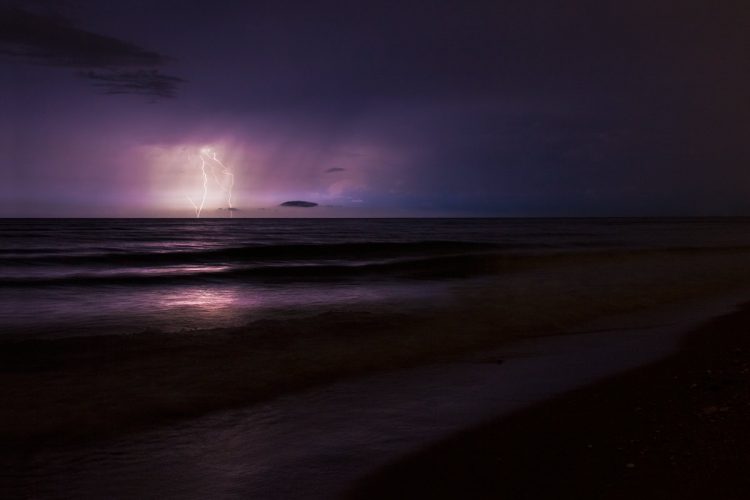 A long exposure photo of lightning striking the ocean at night