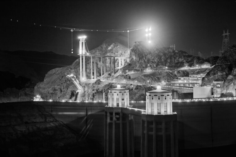 A black and white long exposure photo of the Hoover Dam at night