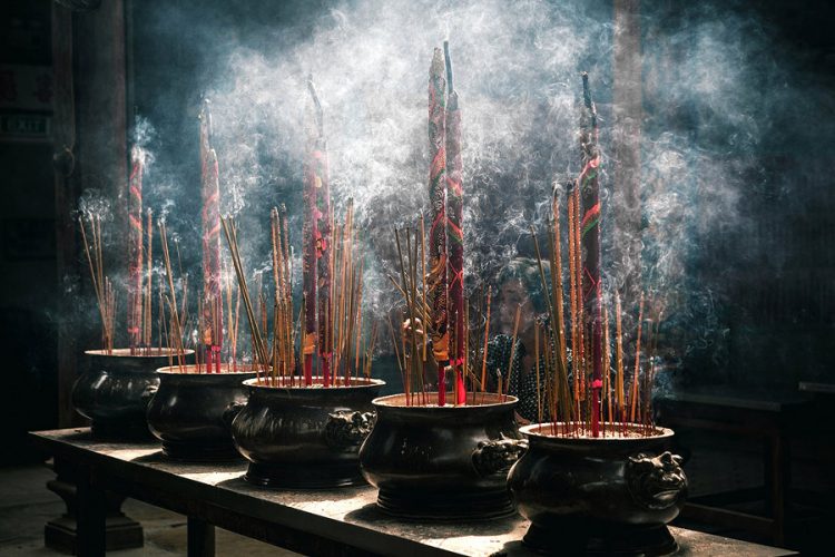 An elderly woman burns incense in the Thien Hau Pagoda, in the heart of Ho Chi Minh City, Vietnam