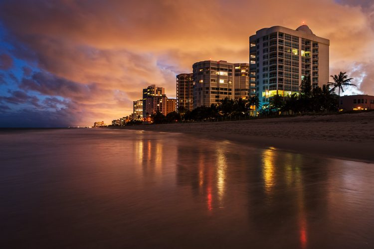 Seascape photo with reflections on the sand from the lights of buildings along the coast